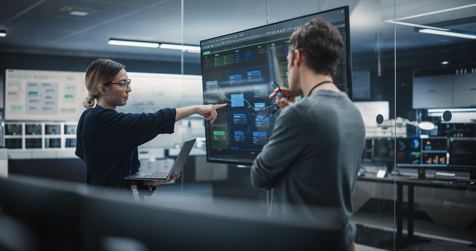 Two IT professionals working in front of a large screen