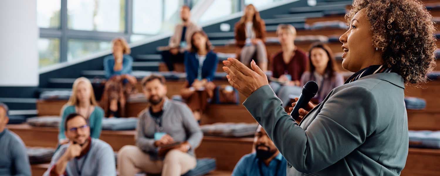 Person with microphone speaking to people in an auditorium